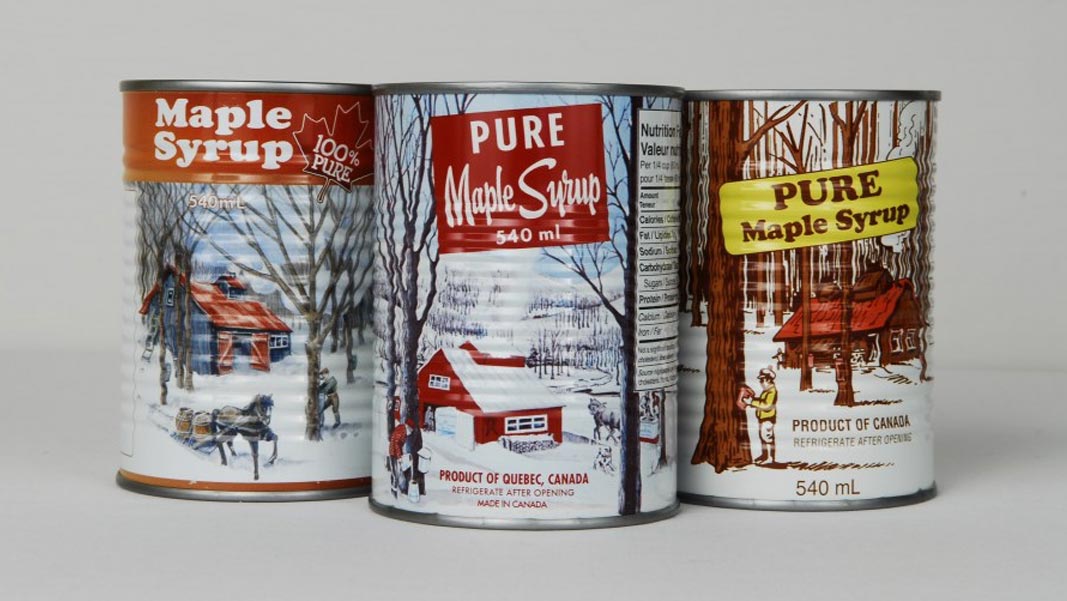 Three cans of maple syrup with traditional lithographic printed labels.