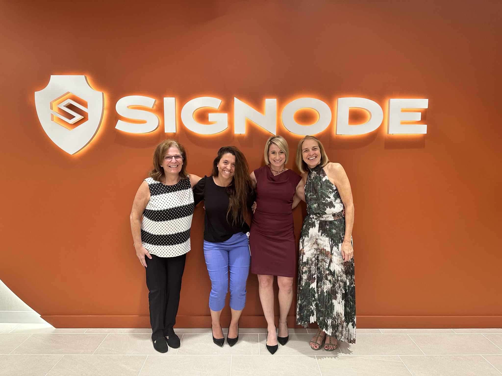 Four women standing together in front of Signode sign