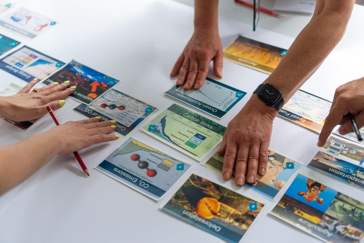 Several people out of frame rearranging different graphs and charts on a desk.