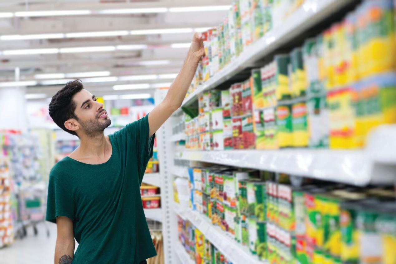 A man reaching for a food can in a grocery store