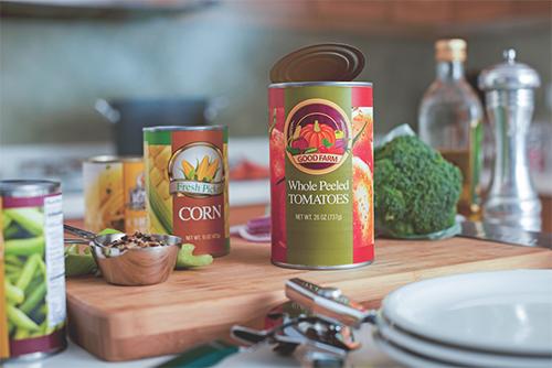 A can of whole peeled tomatoes and corn on a wooden cutting board and white plates.
