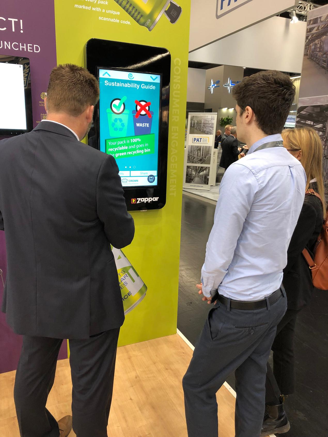 Two people standing in front of a screen that is hanging on the wall.