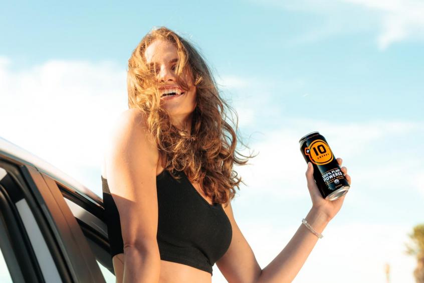 Young woman leaning out window with beverage can in hand
