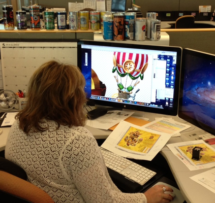Person sitting in front of a computer designing a beverage can package.